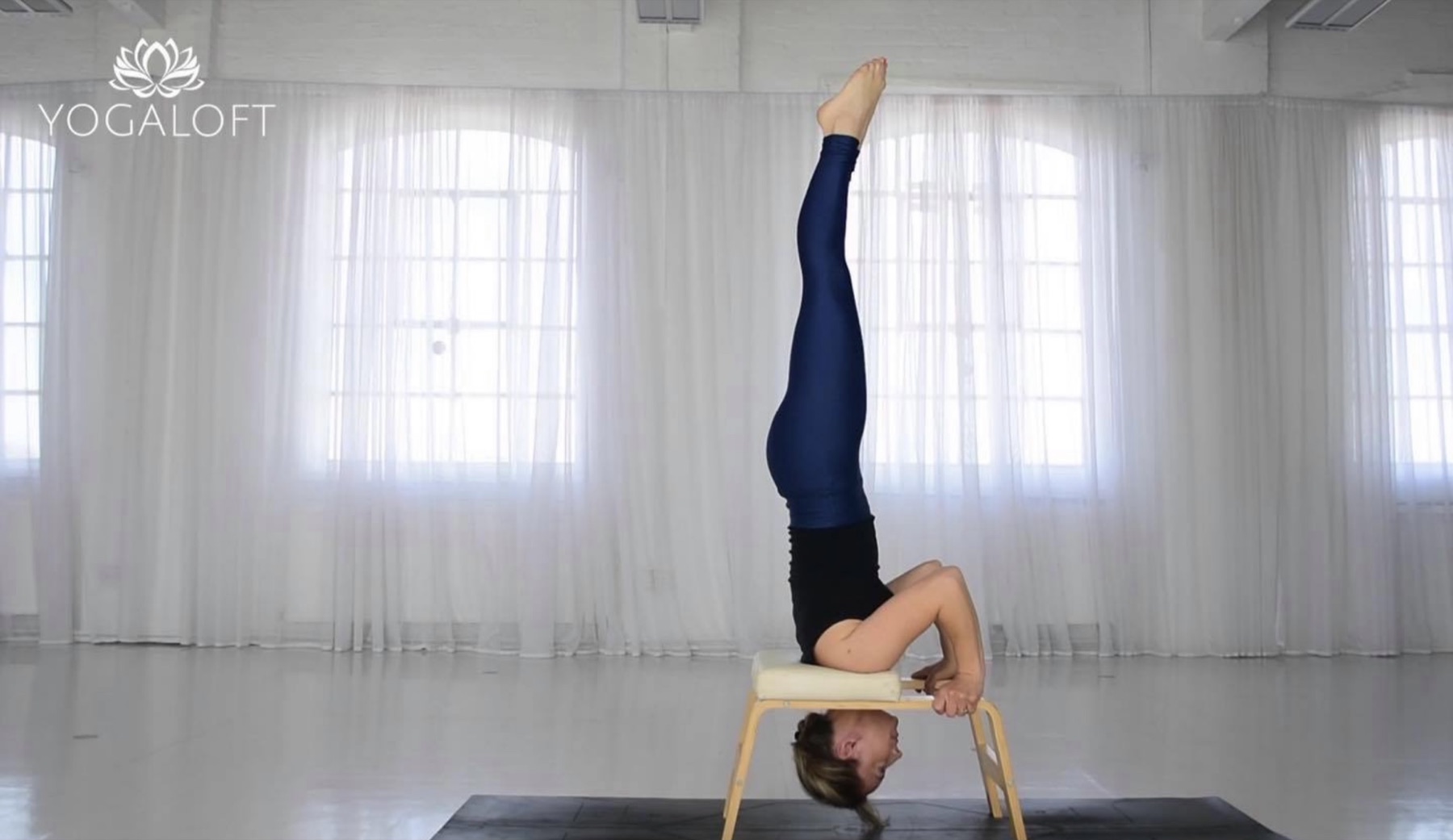 A student in a headstand on a FeetUp Trainer in the studio