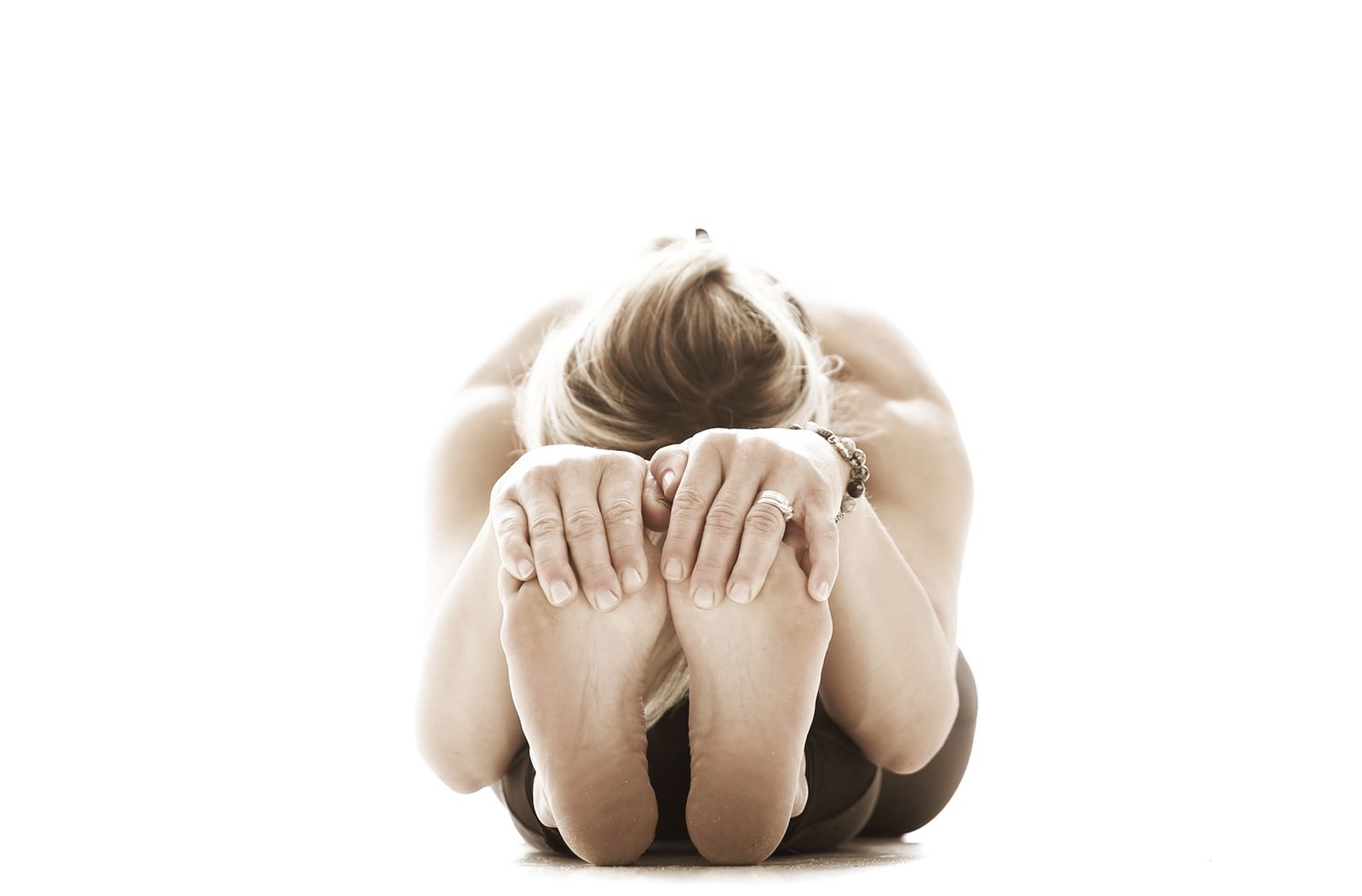 A student folding forward over her legs in a seated forward bend