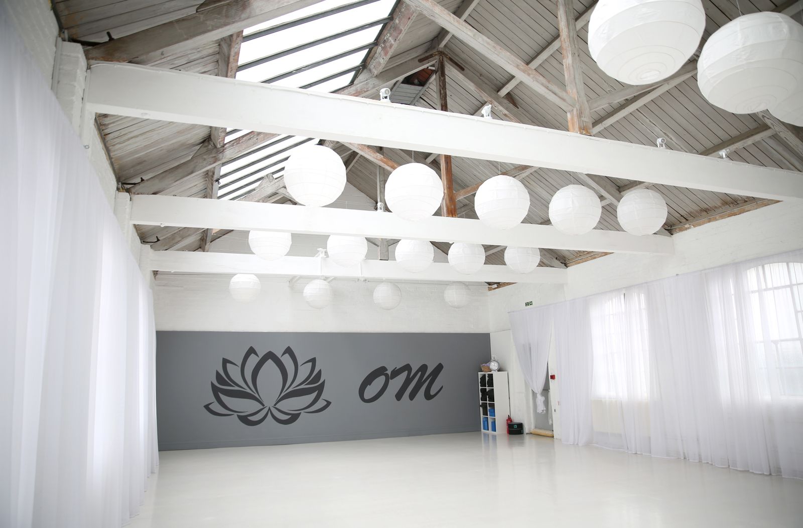 The studio: white beams, paper lanterns and the lotus and om on the grey wall
