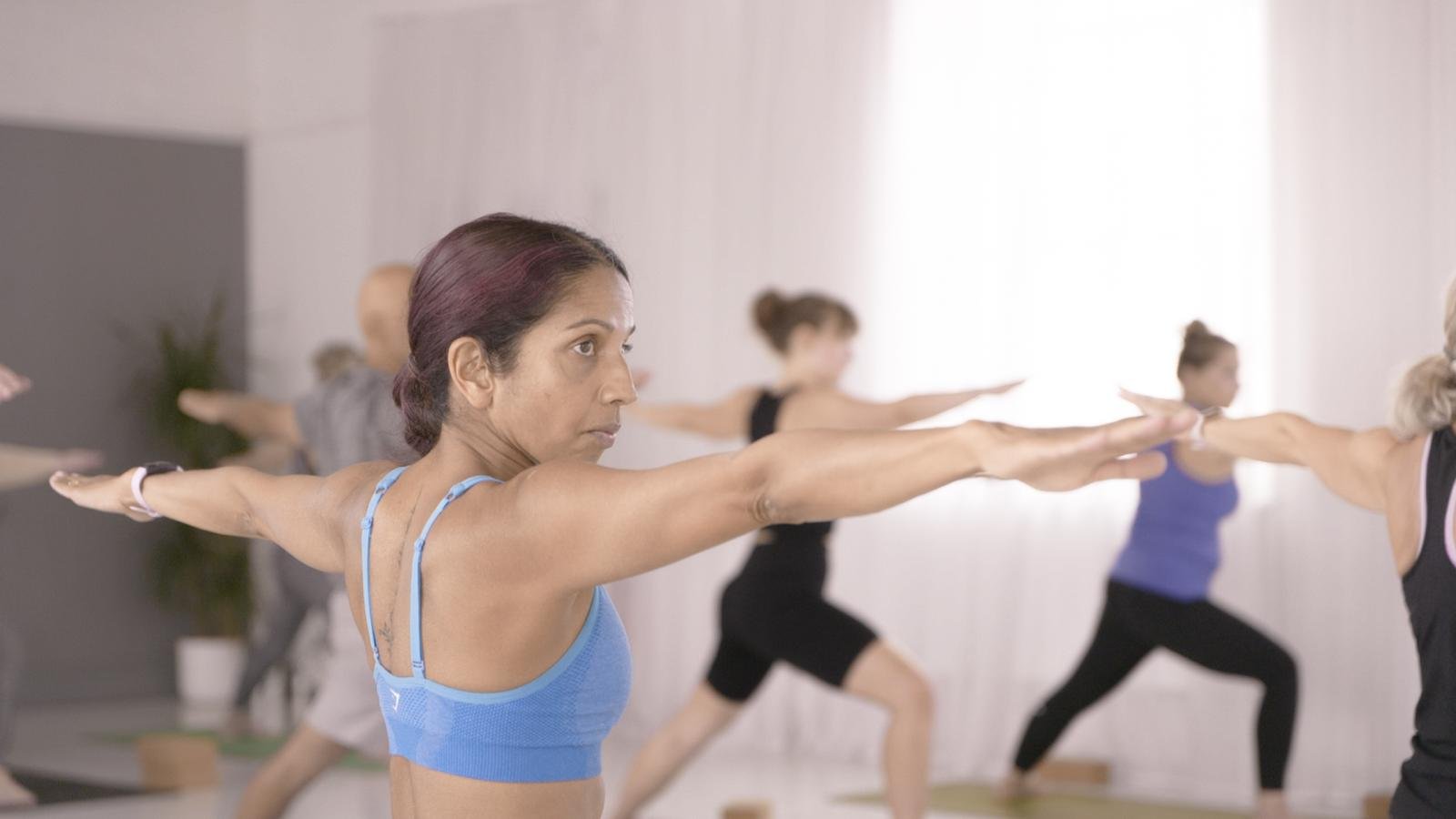 Students holding warrior pose with arms outstretched in a Vinyasa Flow class at The Yoga Loft